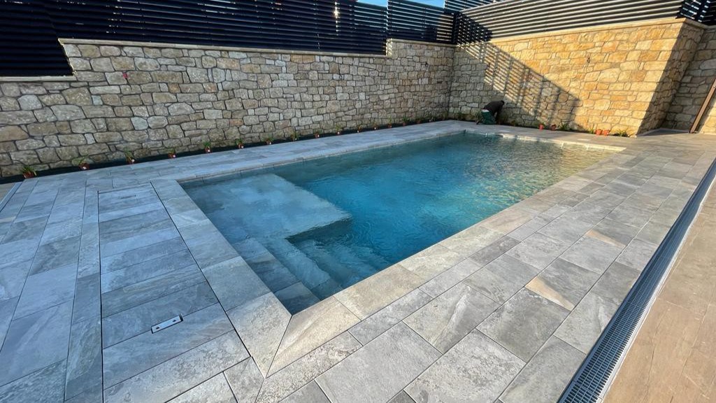 Construcción de piscina de hormigón en jardín mediterráneo